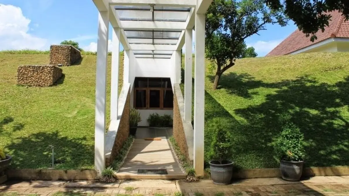 Guest house berkonsep hijau di kompleks Pendopo Sabha Swagata Blambangan, Banyuwangi. Bangunan semi-bawah tanah tersebut memanfaatkan atap tertutup tanah dan rerumputan serta pencahayaan dan sirkulasi udara alami sebagai bagian dari rancangan pasif. (Dok. banyuwangibagus)