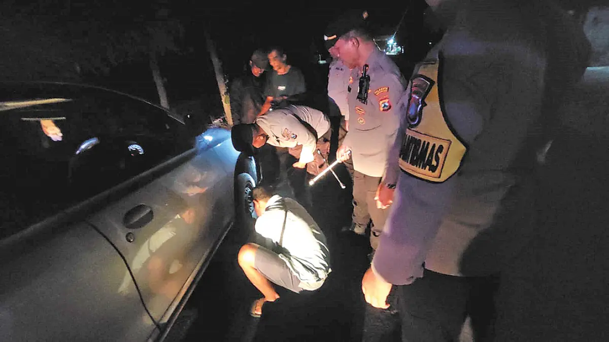 Kapolsek Tegaldlimo AKP Sadimun bersama anggotanya membantu warga mengganti ban mobil yang bocor saat melintas di Jalan Raya Desa Tegaldlimo pada Sabtu malam (19/9). (Sadimun for Radar Banyuwangi)