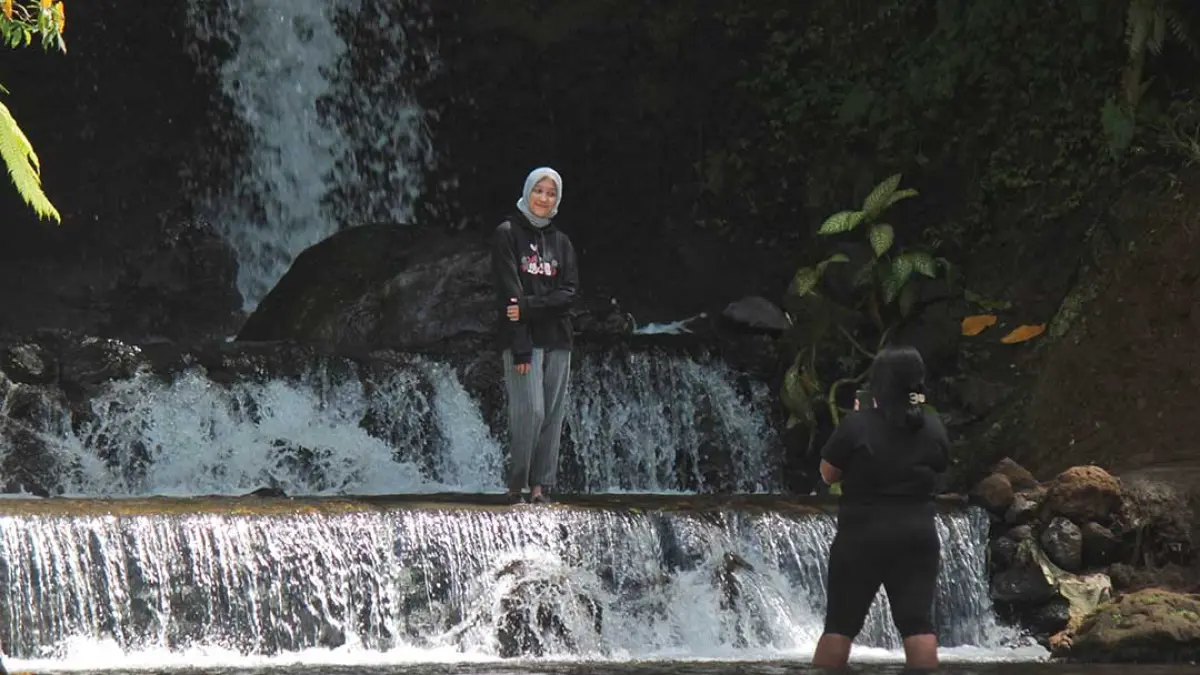 Pengunjung menikmati kesegaran air di Wisata Air Terjun Legomoro di Desa Margomulyo, Kecamatan Glenmore, Jumat (25/9).(Salis Ali/Radar Banyuwangi)