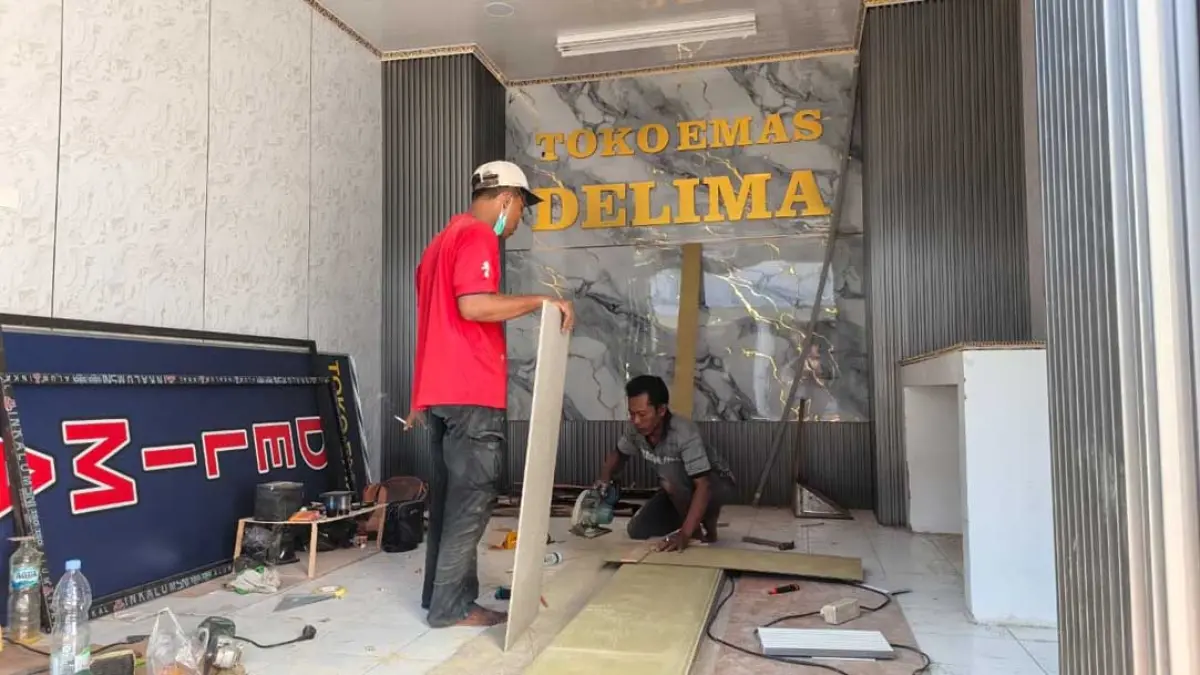 Pekerja menyelesaikan pembuatan sekat meja kayu dan papan reklame di gerai Toko Emas Delima yang berada di dalam bangunan baru Pasar Induk Banyuwangi, Sabtu (26/9). (Ksatria Raya/Radar Banyuwangi)