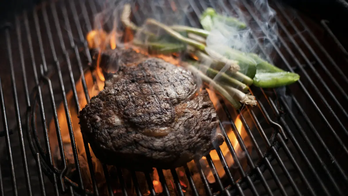 Daging yang dimasak pada suhu tinggi dan terkena asap pembakaran dapat membentuk HCA dan PAH. Bagian yang terlalu hangus disarankan untuk disisihkan. (Unsplash/Edson Saldaña)