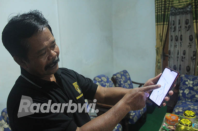 MISTIK: Kades Bayu, Kecamatan Songgon, Sugito menunjukkan denah kampung hilang di gawainya, Minggu (22/5). (Salis Ali/Radar Genteng)