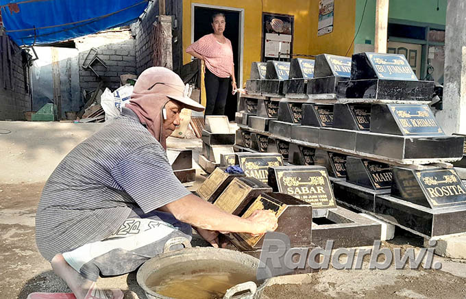 TELATEN: Warsito menggosok nisan yang telah diberi warna di depan rumahnya, Dusun Krajan, Desa Genteng Wetan, Kecamatan Genteng, Kamis (26/5). (Irham Muzaki/Radar Genteng)