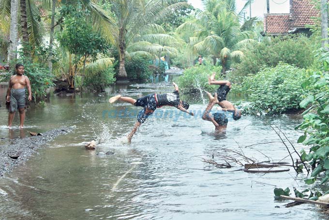 LANGGANAN: Anak-anak bermain air di depan rumah yang tergenang akibat banjir rob di Dusun Krajan, Desa Wringinputih, Kecamatan Muncar yang diterjang banjir rob kemarin (18/5). (Salis Ali/RadarBanyuwangi.id)