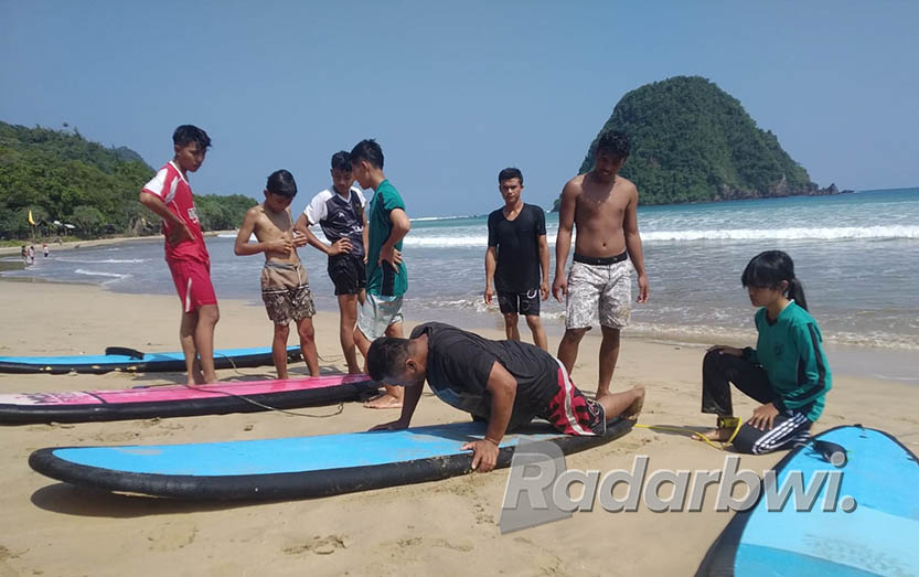 BIBIT PESELANCAR: Sejumlah pelajar peserta pelatihan selancar menyimak pemaparan instruktur di kawasan Pantai Pula Merah, Kecamatan Pesanggaran. (Rofiq for Radar Banyuwangi)
