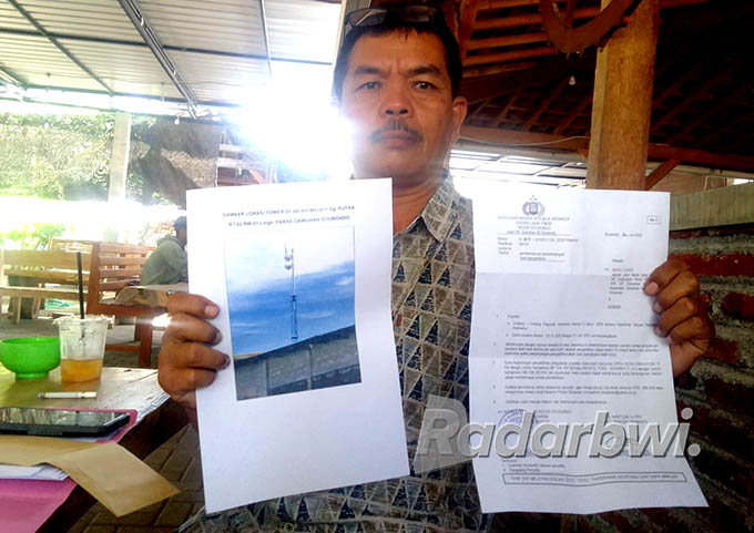 TURUN LAPANGAN: Muhammad Husen menunjukkan gambar tower yang dikeluhkan warga di Lingkungan Perse, Kelurahan Dawuhan, Kecamatan/Kota Situbondo, Kamis (23/6) lalu. (Humaidi/Radar Situbondo)