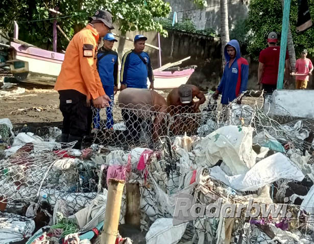 AKIBAT BANJIR ROB: Petugas BPBD Situbondo bersama warga membersihkan tumpukan sampah plastik di Desa Pandean, Kecamatan Banyuputih, Kamis (16/6) kemarin. (Iwan Feriyanto/Radar Situbondo)
