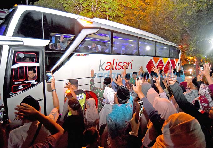 LAMBAIKAN TANGAN: CJH yang tergabung dalam kloter 24 dilepas keluarganya di depan kantor Kemenag Jalan Adi Sucipto Banyuwangi pukul 19.00 tadi malam.  (Ramada Kusuma/RadarBanyuwangi.id)