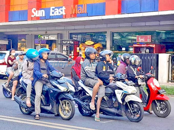 ALAS KAKI: Pengendara motor memakai sandal jepit di jalan simpang empat Desa Genteng Kulon, Kecamatan Genteng, kemarin (19/6). (Irham Muzaki/RadarBanyuwangi.id)