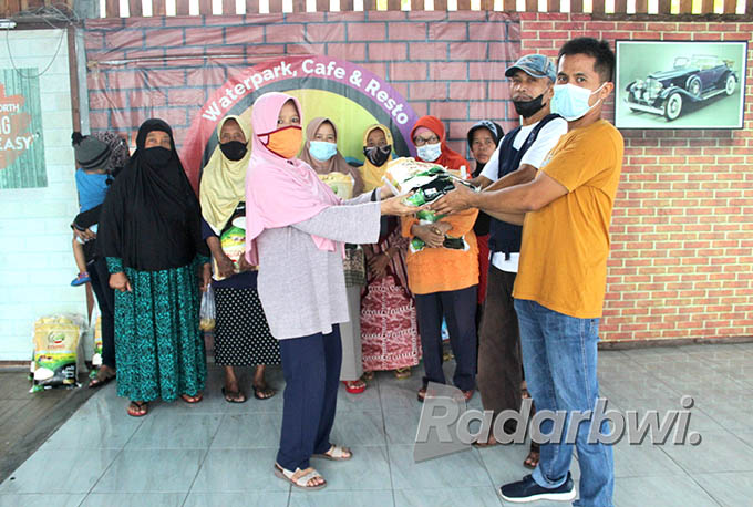 SIMBOLIS: Manajer Cluring Waterpark, Dusun Kepatihan, Desa/Kecamatan Cluring, Bambang (kanan) membagikan beras kepada warga, Kamis (23/6) lalu. (Salis Ali/Radar Banyuwangi)