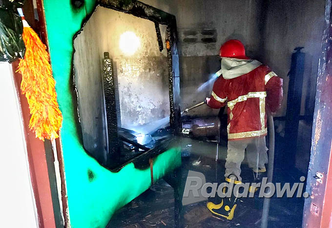 SEMPROT: Anggota Damkar memadamkan api di rumah Tohairi di Dusun Kabat Mantren, Desa Wringinputih, Kecamatan Muncar pada Selasa (21/6) malam. (Maulana for Radar Banyuwangi)