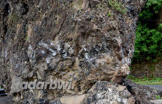 TERKENAL: Batu karang besar membelah ruas jalan nasional yang menghubungkan Banyuwangi dan Situbondo di Desa Ketapang, Kecamatan Kalipuro, Banyuwangi. (Ramada Kusuma/Radar Banyuwangi)
