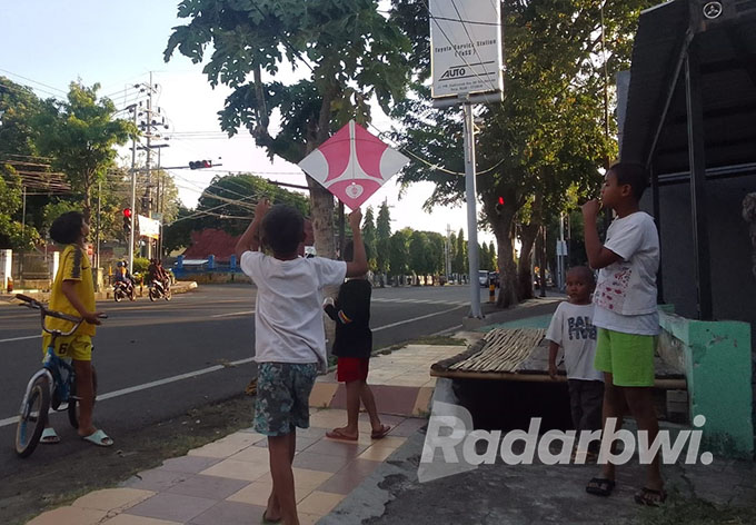 REBUTAN LAYANGAN: Sejumlah anak-anak&nbsp; memperhatikan layangan yang putus di pinggir jalan PB Sudirman, Kelurahan Patokan, Kecamatan /Kota Situbondo, Minggu (10/7). (Humaidi/Radar Situbondo)
