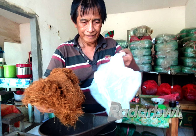 MENIMABANG: Darsuki warga Desa Kayumas, Kecamatan Arjasa, melayani pembeli tembakau, Minggu (17/7) siang. (Humaidi/Radar Situbondo)