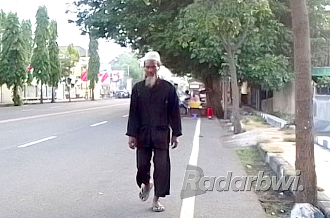 BERJALAN KAKI: Pujono melintas di jalan Pantura Kabupaten Situbondo. (Humaidi/Radar Situbondo)