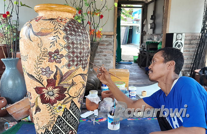 INDAH: Nasihin mengukir batik di pot di rumahnya Dusun Silirsari, Desa Kesilir, Kecamatan Siliragung, Selasa (5/7). (Irham Muzaki/Radar Genteng)
