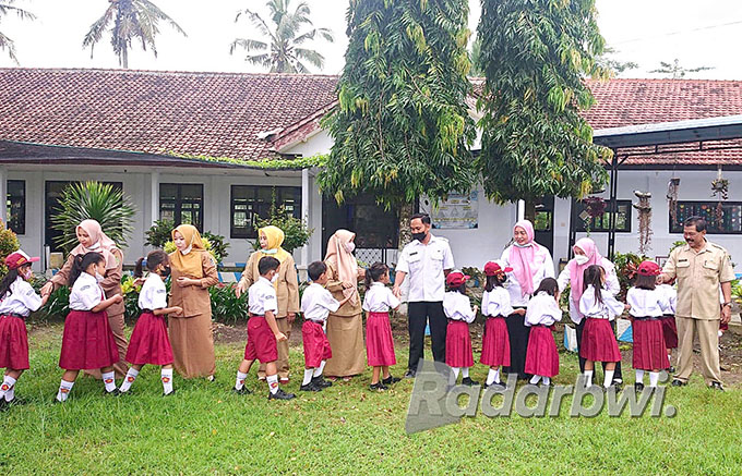 TAKDZIM: Para siswa SDN 3 Kebondalem, Kecamatan Bangorejo salaman dengan para guru setelah upacara bendera di hari pertama masuk sekolah, Senin (18/7). (Irham Muzaki/Radar Genteng)