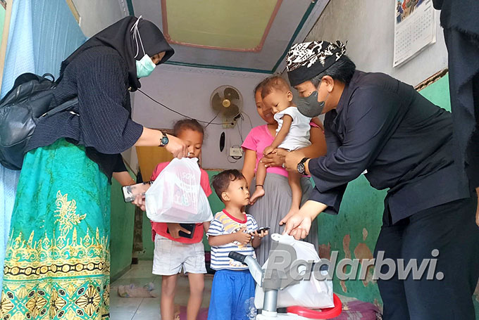 BERBAGI: Kepala Puskesmas Genteng Kulon DR. Yos Hermawan (kanan) membagikan paket nutrisi bergizi untuk anak penderita stunting di Desa Genteng Kulon, Kecamatan Genteng, Kamis (7/7). (Puskesmas Genteng Kulon for Radar Genteng)