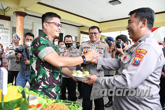 KADO HUT BHAYANGKARA: Dandim Letkol (Kav) Eko Julianto menyerahkan tumpeng kepada Kabag Sumda Kompol Idham Cholid di Polresta Banyuwangi Jumat (1/7). (Bagus Rio/Radar Banyuwangi)