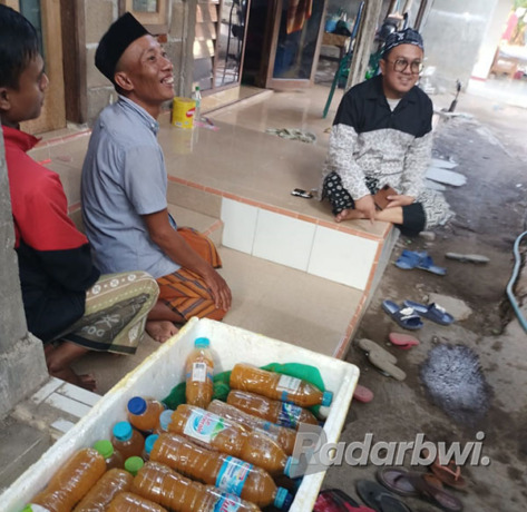 PEDULI: KH Alma’i Sofyan (kanan) memberikan sejumlah botol plastik berisi jamu selawat kepada warga di Kelurahan Mimbaan, Panji, belum lama ini. (Iwan Feriyanto/Radar Situbondo)