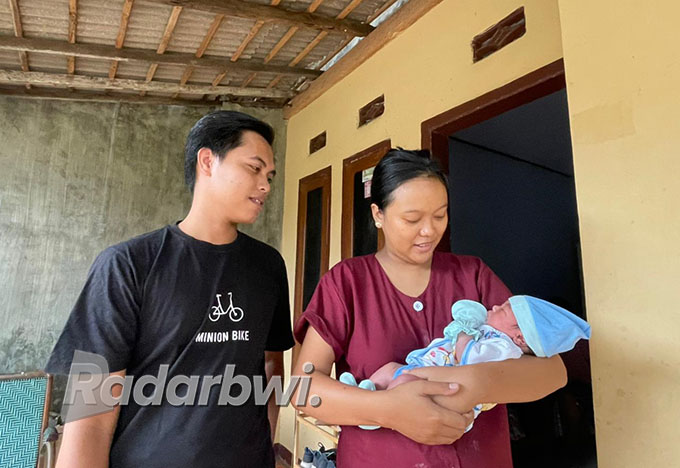 Evi Fitnaningtyas didampingi suaminya, Yuliyanto, menggendong bayinya yang diberi nama Mohamad Arfan Abqory. Selama dalam perawatan di Klinik Firdaus Desa Banjarsari, bayi tersebut tidak rewel.   (Fredy Rizki/Radar Banyuwangi)