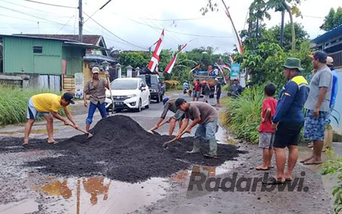 KOMPAK: Warga ramai-ramai menambal jalan berlubang di Dusun Stembel, Desa/Kecamatan Gambiran, Minggu (7/8) pagi. (Rudi for Radar Genteng)