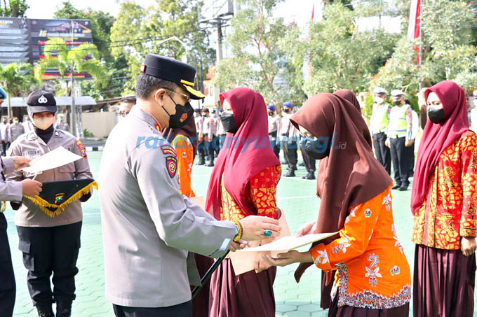 APRESIASI: Kapolresta Banyuwangi Kombespol Deddy Foury Millewa (kiri) memberikan penghargaan kepada para anggota Sanggar Tari Sayu Wiwit di halaman Polresta Banyuwangi kemarin (22/8) (Bagus Rio/RadarBanyuwangi.id)