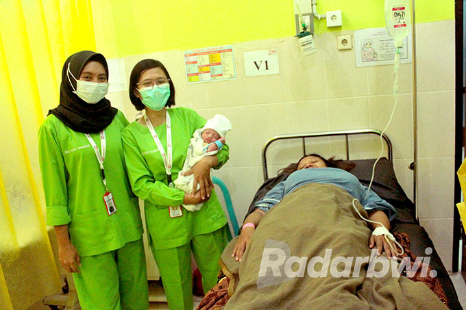 PENUH SYUKUR: Dua perawat di ruang bersalin RSUD Genteng menggendong bayi yang baru dilahirkan Dewi Deswita pada HUT ke-77 RI, Rabu (17/8). (Salis Ali/Radar Genteng)