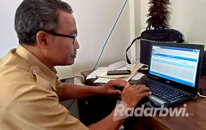 SIBUK: Kepala Seksi Pemerintahan Kecamatan Kabat Sucipto sedang sibuk di ruangannya, Selasa (27/9). (Ayu Lestari/Radar Banyuwangi)