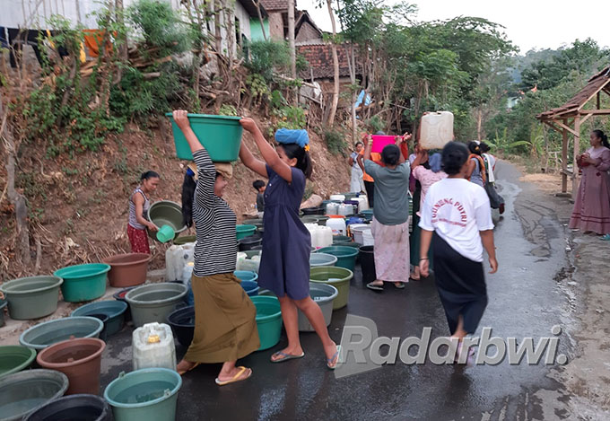 TERJADI TIAP TAHUN: Petugas BPBD Situbondo mengisi wadah yang disediakan warga untuk air bersih, di Dusun Jambangan Timur Desa Plalangan, Kecamatan Sumbermalang, Jumat (2/9) lalu. (BPBD for Radar Situbondo)