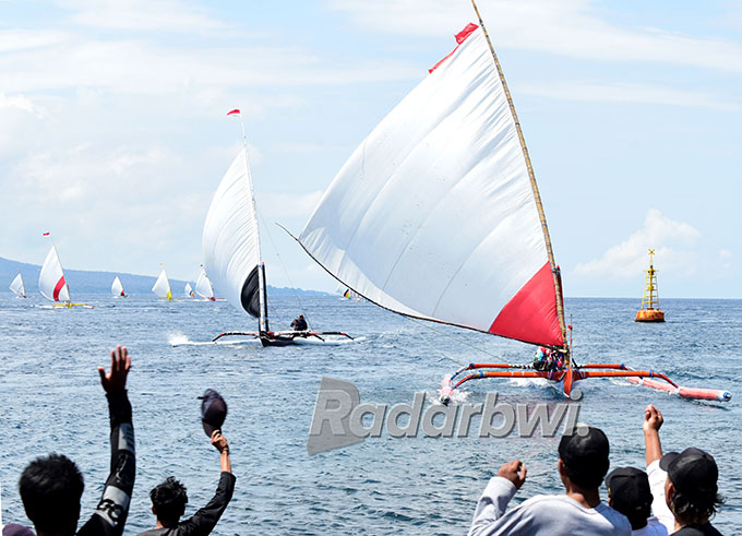 ANDALKAN KECEPATAN ANGIN: Penonton menyemangati peserta lomba perahu layar yang mengambil start di Pantai Waru Jejer, Kelurahan Bulusan, Kecamatan Kalipuro, Rabu (7/9). (Ramada Kusuma/Radar Banyuwangi)
