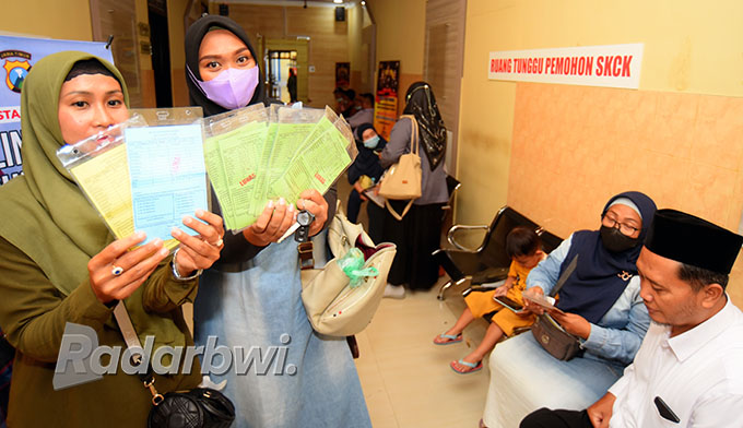 BEBERKAN BARANG BUKTI: Wali murid MIN 1 Banyuwangi menunjukkan kartu infak dan sedekah ketika melapor di Mapolresta Banyuwangi, Selasa (27/9).   (Ramada Kusuma/Radar Banyuwangi)