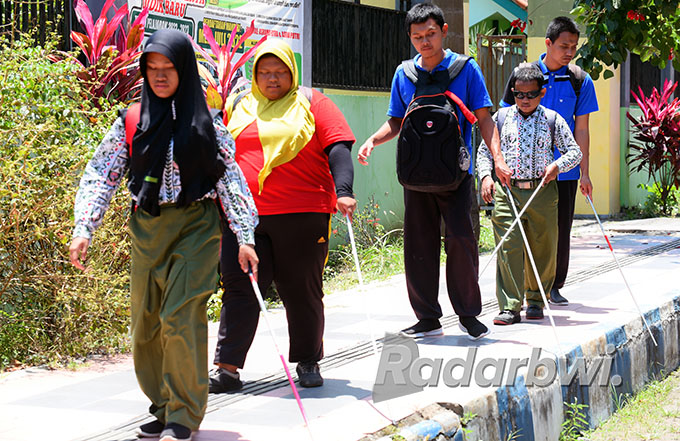 Siswa SMALB  Banyuwangi berjalan di trotoar yang belum didesain khusus untuk penyandang disabilitas di Jalan Wijaya Kusuma, Selasa (28/9). Pedestrian di Taman Blambangan dirancang ramah difabel. (Ramada Kusuma/Radar Banyuwangi)