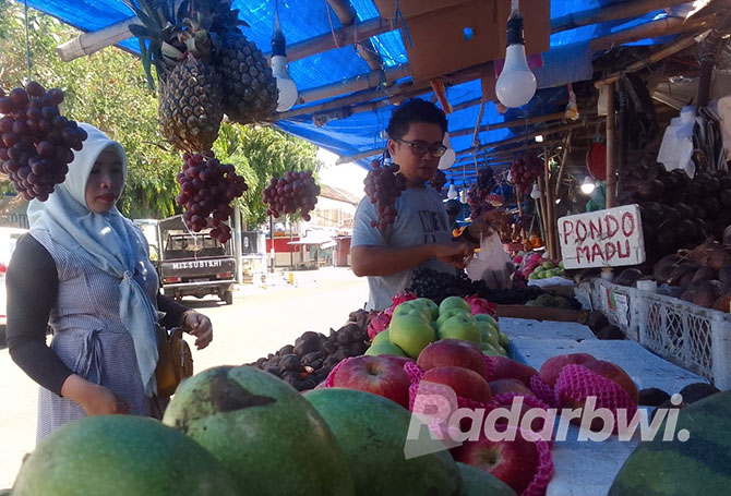 TAWAR MENAWAR: Eko warga Kelurahan/Kecamatan Panji, memilih buah untuk diberikan kepada pembelinya, di Pasar Mimbaan Baru, Minggu (9/10). (Humaidi/Radar Situbondo)