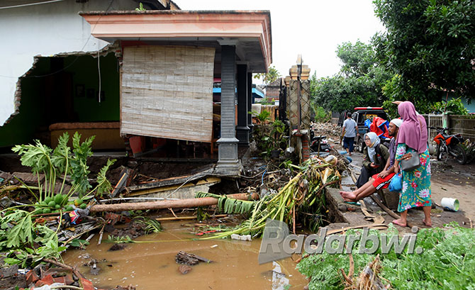 PASRAH: Pasutri Nur Setyo (pakai peci) dan Masriah (daster hijau) melihat kondisi rumahnya sesudah diterjang banjir di Kelurahan Sobo, Kecamatan Banyuwangi, Selasa (18/10). (Ramada Kusuma/Radar Banyuwangi)