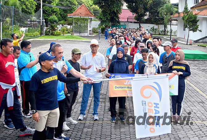 START: Kepala KPP Pratama Banyuwangi Eko Budihartono (pakai topi) didampingi pimpinan KPPN Banyuwangi mengibarkan bendera simbol pemberangkatan peserta jalan sehat di halaman KPP Pratama Banyuwangi, Jumat (21/10). (Ramada Kusuma/Radar Banyuwangi)