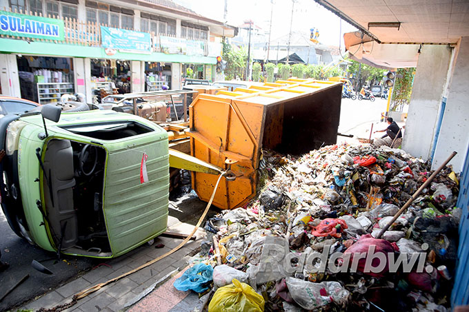 MENGGUNUNG: Truk milik DLH terguling di kawasan simpang empat Lateng, Kecamatan Banyuwangi, Senin (10/10). Sampah yang diangkut tumpah hingga memenuhi trotoar Jalan M.H. Thamrin. (Ramada Kusuma/Radar Banyuwangi)