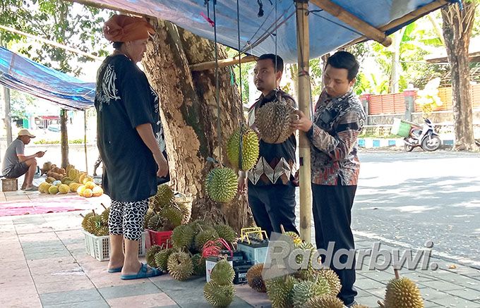 MENJUAL DURIAN: Muin melayani dua pembeli durian di trotoar Jalan Wijayakusuma, Selasa (4/10). (Lugas Rumpakaadi/Radar Banyuwangi)