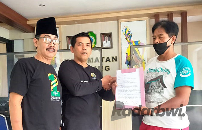BATAL: Kades Yudi Wiyono (tengah) didampingi Kades Sraten Arif Rahman Mulyadi (kiri) menyerahkan surat pencabutan pengunduran diri pada staf kantor Kecamatan Cluring, Jumat (21/10). (Abidin untuk Radar Genteng)