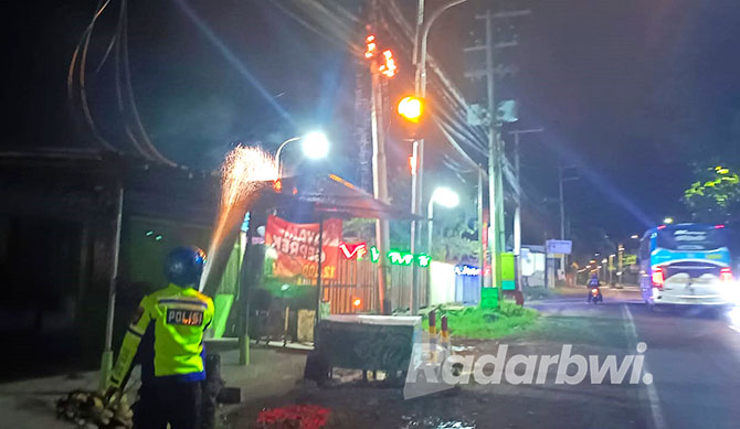 NYARIS HANGUS: Anggota Satlantas Polresta Banyuwangi memadamkan api di rumah Agus Bandi, warga Lingkungan Tanjung, Kelurahan Klatak, Kecamatan Kalipuro. (Satlantas untuk Radar Banyuwangi)