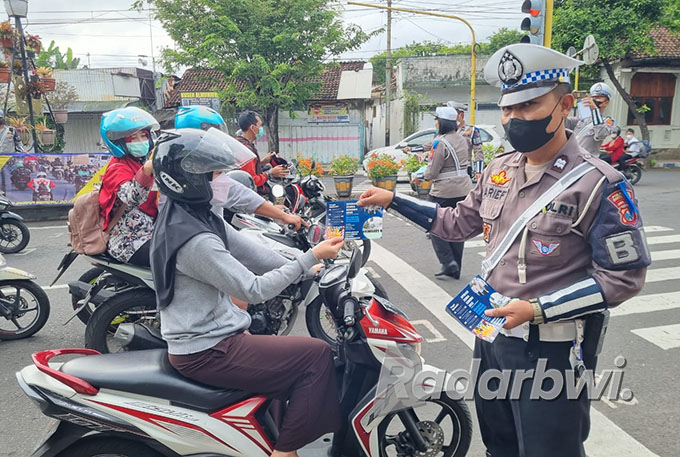 DIIMBAU TERTIB: Anggota Satlantas membagikan brosur kepada pengendara sepeda motor yang melintas di Jalan Jaksa Agung Suprapto, Banyuwangi, Rabu (5/10). (Kanit Turjawali for RaBa)