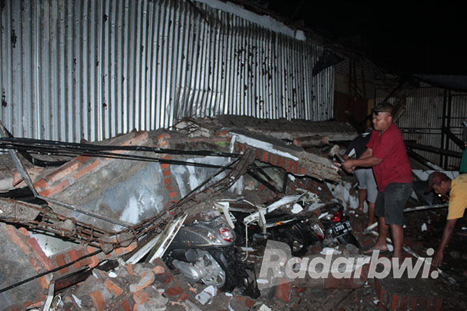 EVAKUASI: Warga mengevakuasi reruntuhan bangunan atap teras Indomaret di Dusun Klontang, Desa Gendoh, Kecamatan Sempu yang roboh menimpa enam motor, Senin (17/10) petang. (Salis Ali/Radar Genteng)