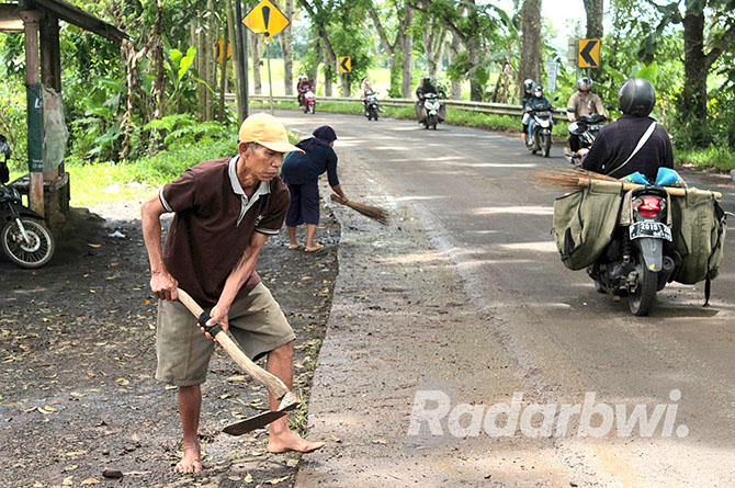 PEDULI: Salah satu warga membersihkan lumpur yang menempel di bahu jalan sekitar Jembatan SasakMayit Dusun Nganjukan, Desa Karangsari, Kecamatan Sempu dipenuhi lumpur, Kamis (20/10). (Salis Ali/Radar Genteng)