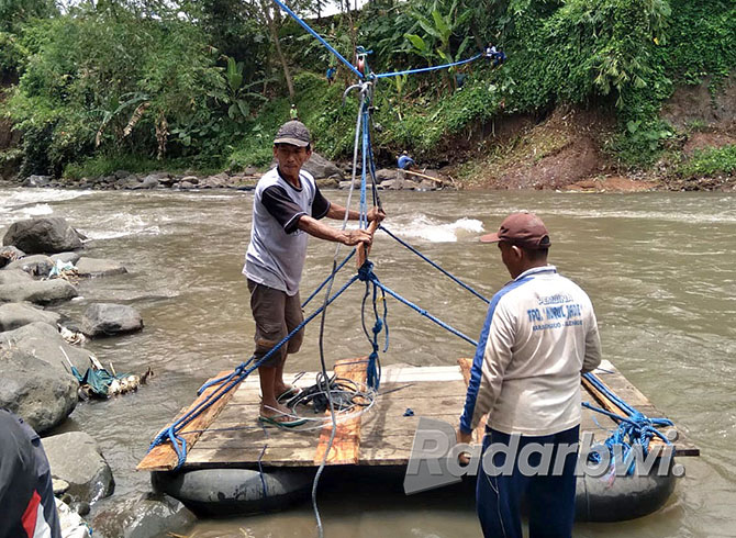 TERPAKSA: Warga melintasi aliran Sungai Kalibaru menggunakan rakit dari ban mobil bekas, Jumat (28/10). (Salis Ali/Radar Genteng)