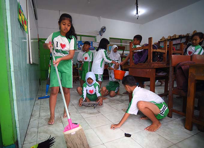 Sejumlah Siswa membersihkan ruang kelas dari genangan banjir yang menerjang sekolah SDN Lateng