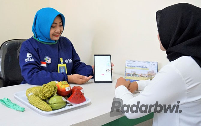MAJU: Petugas Gizi Irhamni Setyaningrum SST melakukan konsultasi dengan menggunakan aplikasi NIPPON di Rustida Krikilan, Glenmore, Banyuwangi. (RUSTIDA FOR JPRG)
