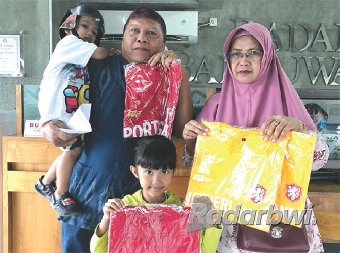 BORONG KAUS: Sukoro, loper koran Banyuwangi bersama keluarga kembali memesan empat kaus timnas Piala Dunia di kantor Jawa Pos Radar Banyuwangi, Senin (7/11). (Aulina Tiasih/Radar Banyuwangi)