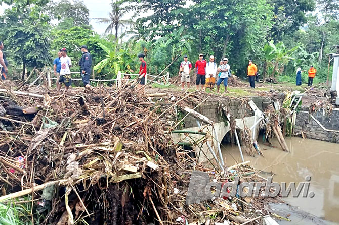 TURUN KE LAPANGAN: Personel BPBD memeriksa sisa material banjir yang terjadi di RT 04/ RW 05 Dusun Gunung Remuk, Desa Ketapang, Kecamatan Kalipuro, Minggu (20/11). (BPBD UNTUK RABA)