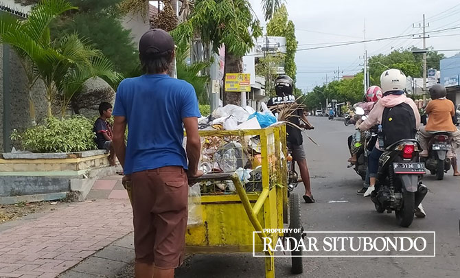 DIDORONG: Seseorang sedang membawa sampah menggunakan gerobak ke tempat pembuangan sementara, di Kelurahan Mimbaan Kecamatan Panji, Rabu (30/11). (IWAN FERIYANTO/JPRS)