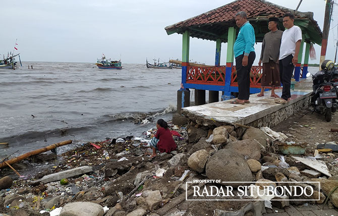 MERENUNG: Sejumlah warga di dampingi Anggota DPRD Situbondo, Suprapto mengecek bangunan tanggula yang rusak akibat banjir rob, Sabtu (24/12) lalu. (IWAN FERIYANTO/JPRS)